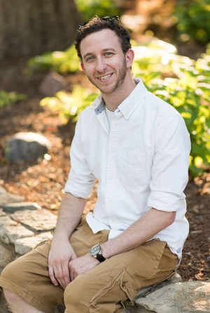 Therapist Joshua Wolfinsohn's headshot sitting outdoors wearing khaki pants and white shirt