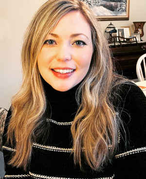 Therapist Kayleen Reardon's headshot indoors wearing a black striped sweater
