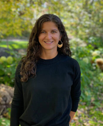 Therapist Edvina LeBoeuf's headshot standing outdoors by green trees, wearing a black top