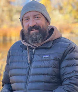 Therapist James "Raven" Miller Headshot standing outdoors, smiling, wearing a black jacket and grey beanie