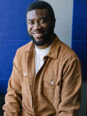 Headshot of therapist Kiani Mitchell smiling and wearing a beige button up shirt