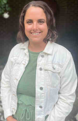 Therapist Sydney Bartel's headshot wearing a white top outside