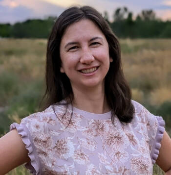 Photo of Therapist Charlotte Hamilton, standing outdoors, wearing a floral blouse and smiling