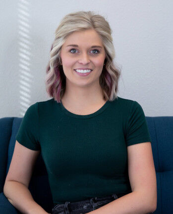 Photo of Therapist Jordyn Schneider, sitting down, smiling, wearing a dark green shirt