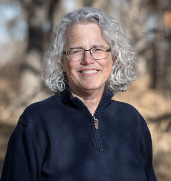 Photo of therapist Melody Jones, standing outside, wearing a dark blue jacket, smiling.