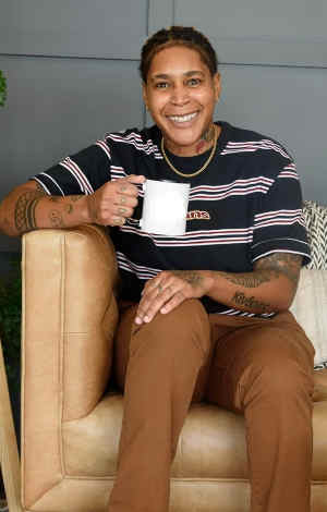 Photo of therapist Shana Dobson, sitting in a chair, smiling with a coffee cup.