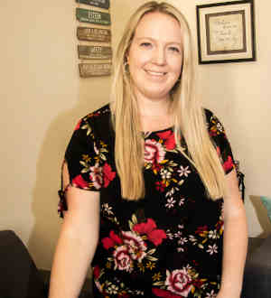 Photo of provider Julie Bledsoe, standing in an office, smiling, wearing a floral shirt.