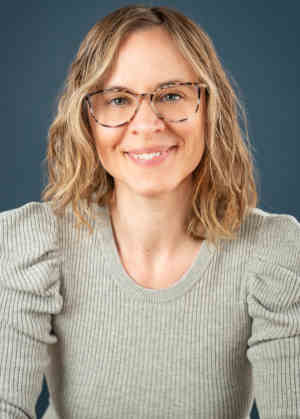 Photo of therapist Maria Lebovich, wearing a grey shirt, smiling.