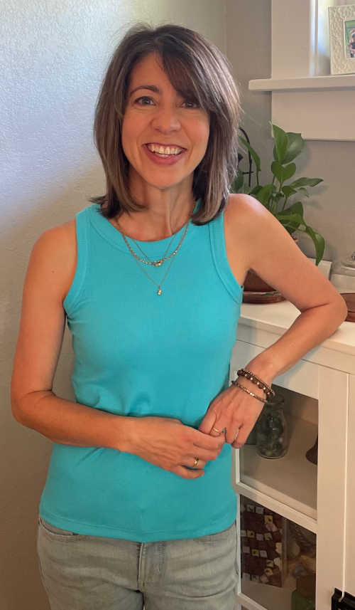 Therapist Angela Romero, standing in an office, smiling, wearing a blue shirt.