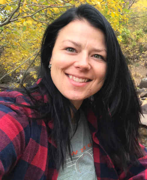 Photo of therapist Heather Krause, with long dark hair wearing a flannel shirt, smiling.